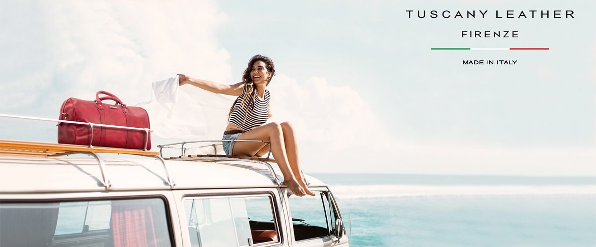 Red leather travel bag on a camper van beside the sea